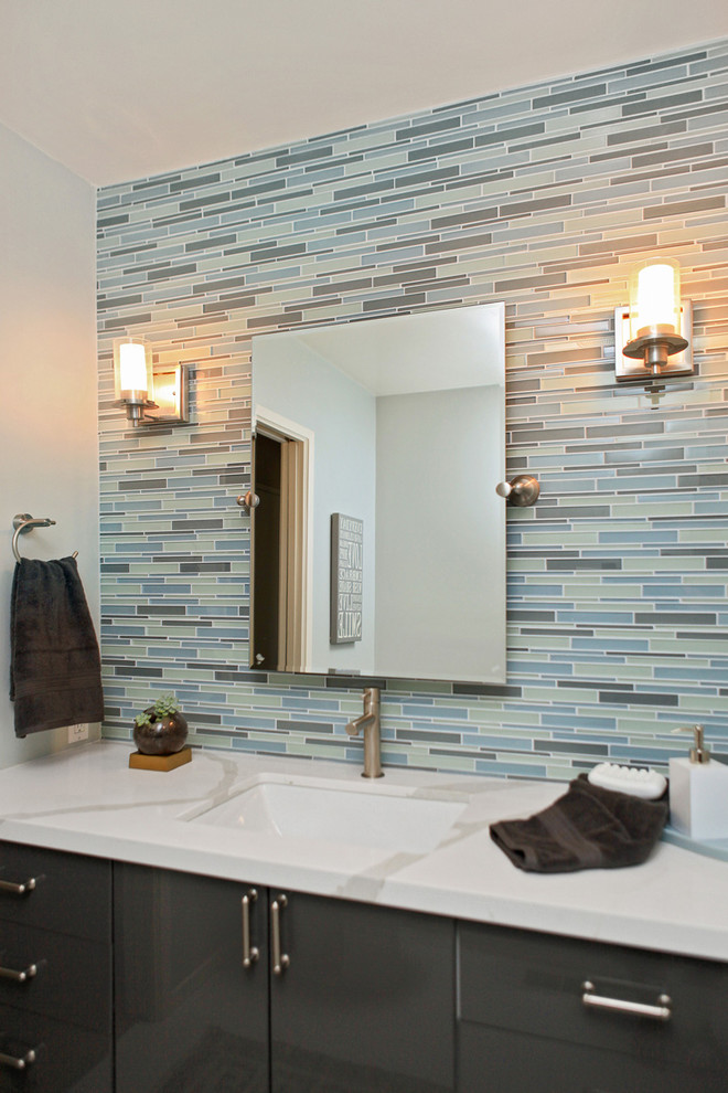 На фото: ванная комната среднего размера в стиле модернизм с врезной раковиной, плоскими фасадами, серыми фасадами, столешницей из искусственного кварца, разноцветной плиткой, удлиненной плиткой, серыми стенами и полом из керамогранита с