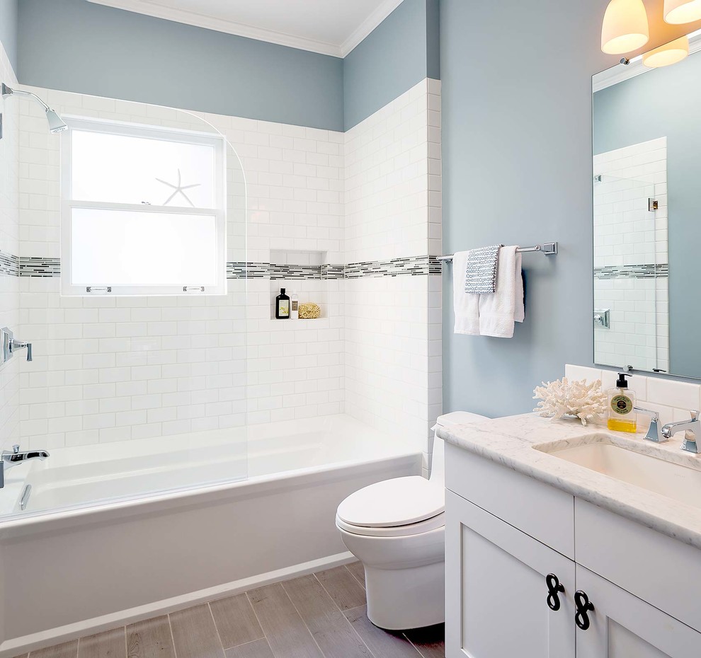 サンフランシスコにあるお手頃価格の小さなビーチスタイルのおしゃれなマスターバスルーム (アンダーカウンター洗面器、シェーカースタイル扉のキャビネット、白いキャビネット、大理石の洗面台、アルコーブ型浴槽、白いタイル、サブウェイタイル、青い壁、磁器タイルの床、シャワー付き浴槽	、一体型トイレ	、緑の床、開き戸のシャワー、白い洗面カウンター) の写真
