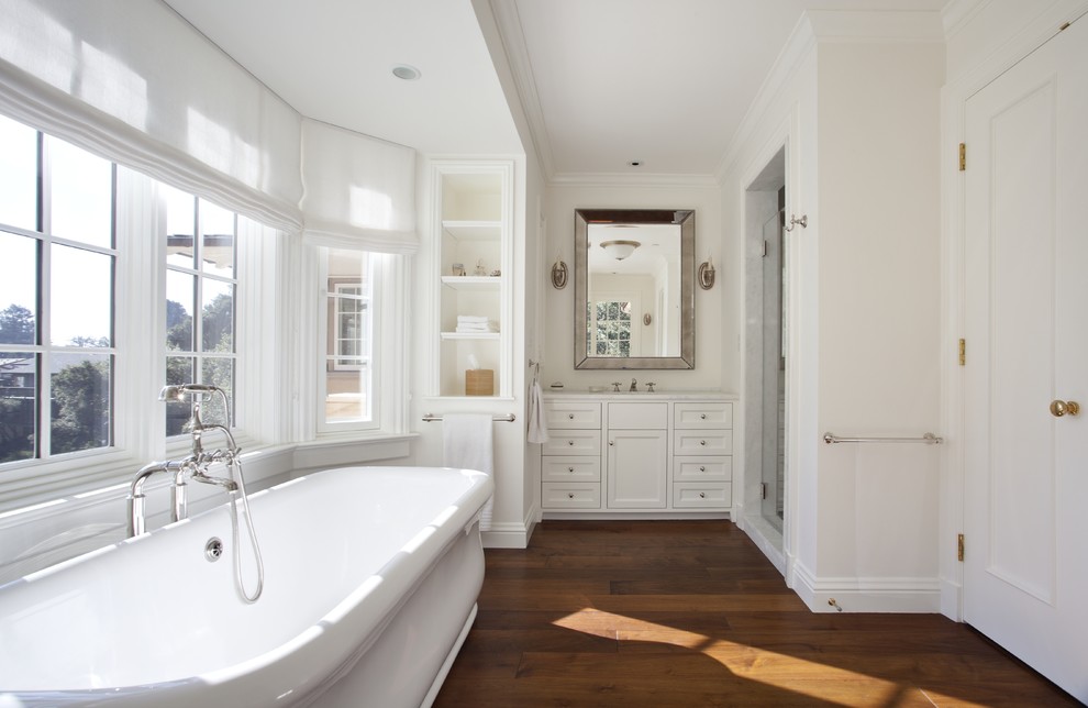 Foto de cuarto de baño rectangular clásico con bañera exenta, suelo de madera en tonos medios y suelo marrón