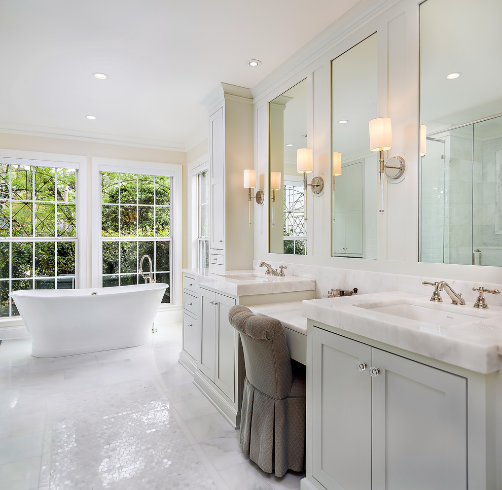 Modelo de cuarto de baño principal tradicional con armarios estilo shaker, puertas de armario grises, bañera exenta, paredes beige, lavabo bajoencimera, suelo blanco y encimeras beige