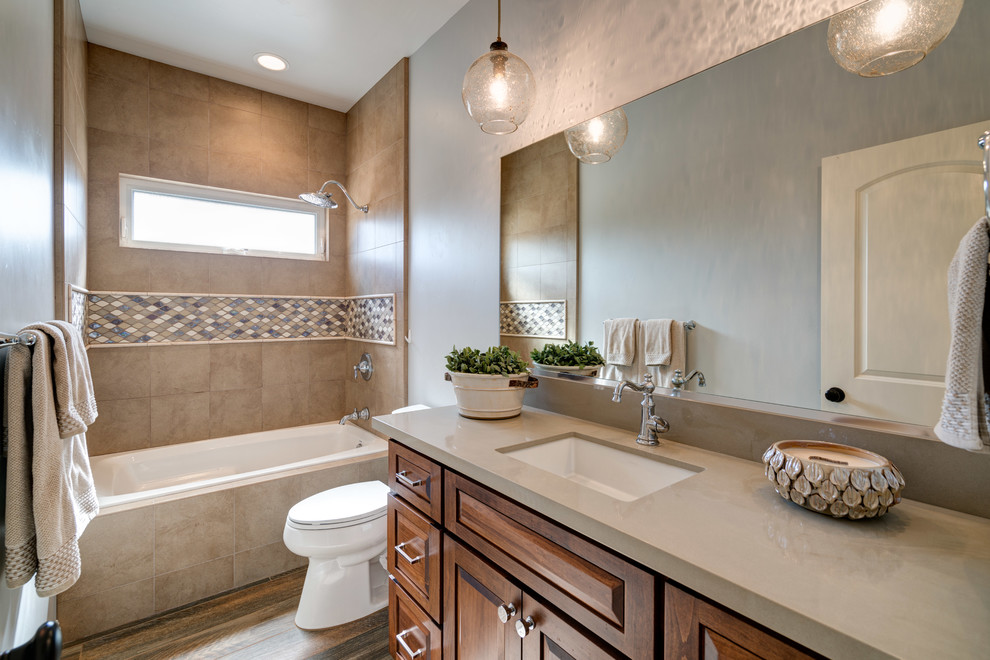 Alcove bathtub - mid-sized transitional 3/4 beige tile porcelain tile and multicolored floor alcove bathtub idea in San Diego with raised-panel cabinets, medium tone wood cabinets, beige walls, an undermount sink, quartz countertops and beige countertops