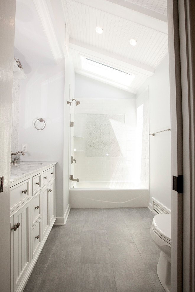 Inspiration for a small transitional master white tile and porcelain tile porcelain tile tub/shower combo remodel in New York with furniture-like cabinets, white cabinets, a one-piece toilet, blue walls, an undermount sink and marble countertops