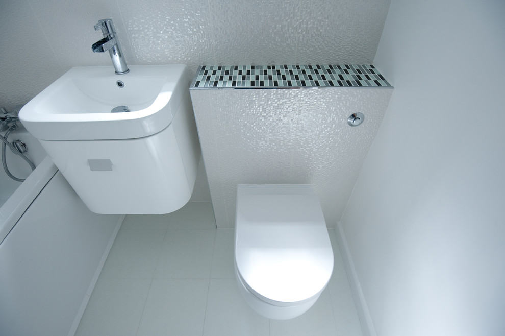 Ispirazione per una piccola stanza da bagno design con vasca da incasso, vasca/doccia, WC monopezzo, piastrelle multicolore, pareti bianche, lavabo sospeso e top piastrellato