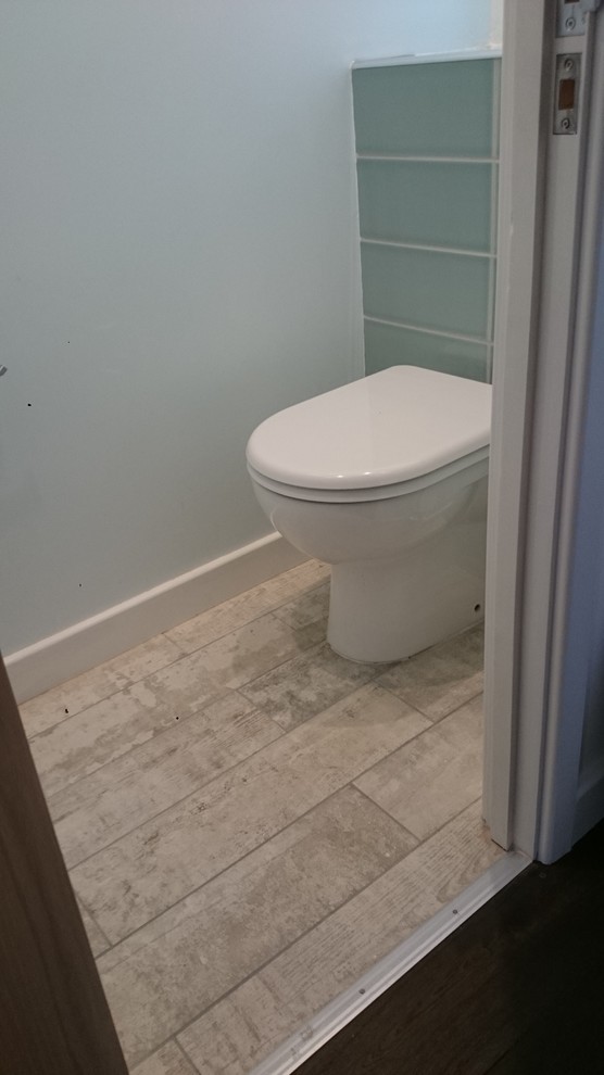 Idee per una piccola stanza da bagno per bambini minimalista con piastrelle grigie, vasca/doccia, ante lisce, ante bianche, vasca da incasso, WC monopezzo, lavabo sospeso, pareti bianche e piastrelle in ceramica