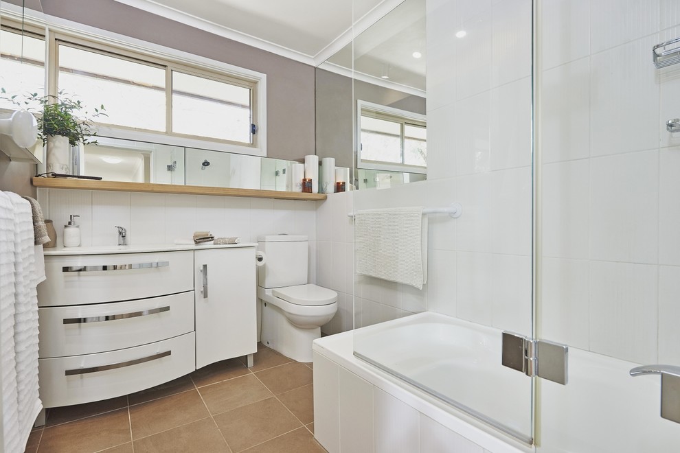 Photo of a small traditional shower room bathroom in Melbourne with a built-in bath, a shower/bath combination, a one-piece toilet, white tiles, ceramic tiles, brown walls, ceramic flooring and an integrated sink.