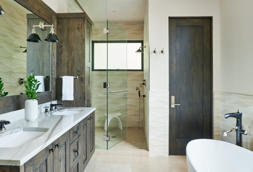 Medium sized traditional ensuite bathroom in Denver with a freestanding bath, shaker cabinets, medium wood cabinets, an alcove shower, beige tiles, beige walls, a submerged sink, beige floors, a hinged door, white worktops, a two-piece toilet, ceramic tiles, porcelain flooring and marble worktops.