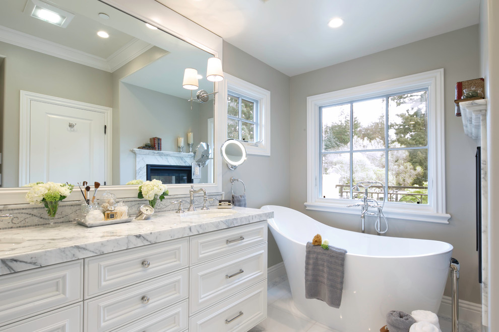 Elegant freestanding bathtub photo in San Francisco with an undermount sink, recessed-panel cabinets, white cabinets and gray walls