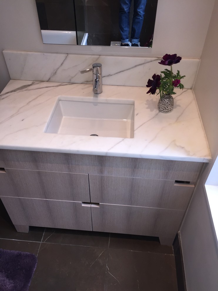 Small contemporary ensuite bathroom in Philadelphia with freestanding cabinets, light wood cabinets, a freestanding bath, a wall mounted toilet, white tiles, stone slabs, beige walls, marble flooring, a submerged sink and marble worktops.