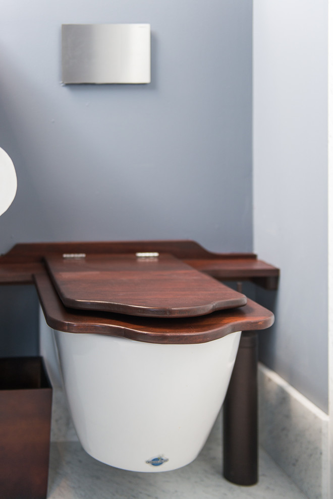Cette image montre une salle de bain minimaliste en bois brun de taille moyenne avec un placard à porte shaker, une baignoire en alcôve, un bidet, un carrelage noir, des carreaux en allumettes, un mur beige, parquet clair, un lavabo de ferme et un plan de toilette en zinc.