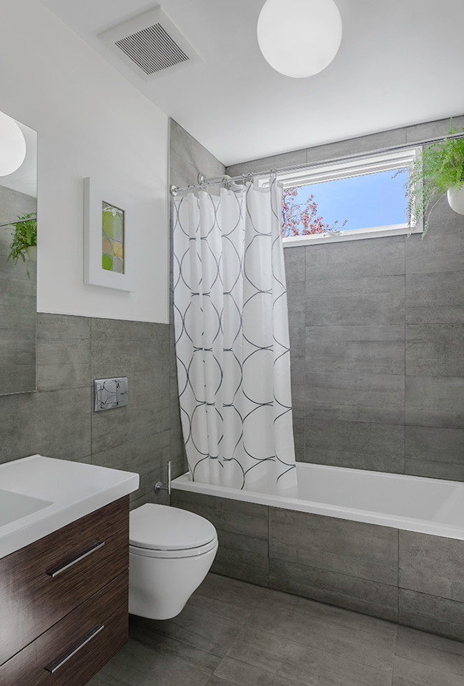 Immagine di una stanza da bagno per bambini moderna di medie dimensioni con vasca da incasso, vasca/doccia, piastrelle grigie, piastrelle di cemento, pareti bianche e pavimento con piastrelle in ceramica