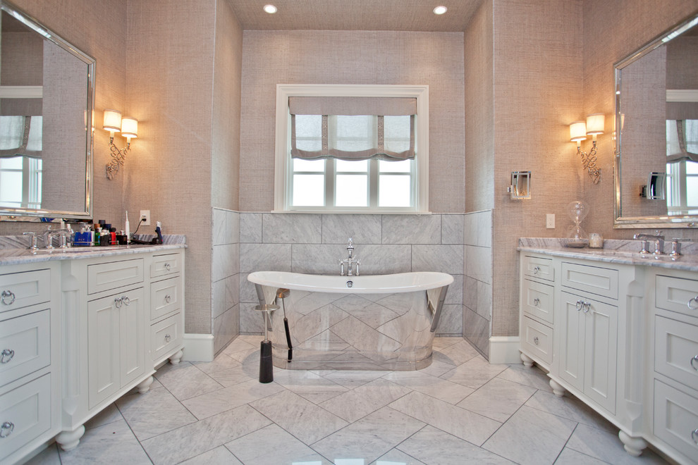 Inspiration for a medium sized classic ensuite bathroom with recessed-panel cabinets, white cabinets, a freestanding bath, beige tiles, marble tiles, marble flooring, a submerged sink, granite worktops, white floors and beige worktops.