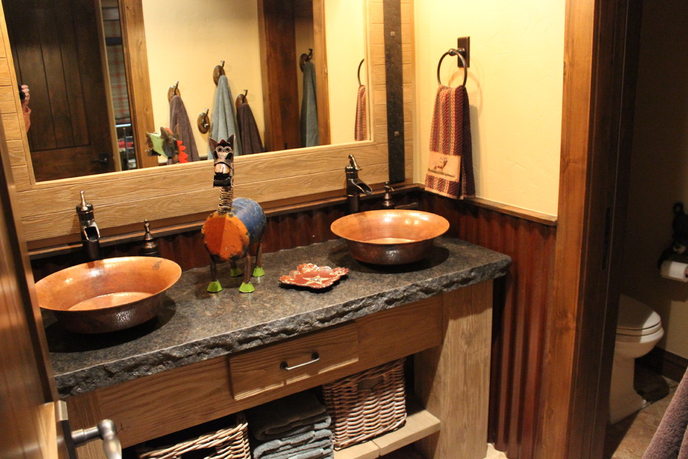 Diseño de cuarto de baño tradicional con armarios tipo mueble, puertas de armario de madera oscura, paredes beige, lavabo sobreencimera, encimera de granito, sanitario de una pieza y suelo de travertino