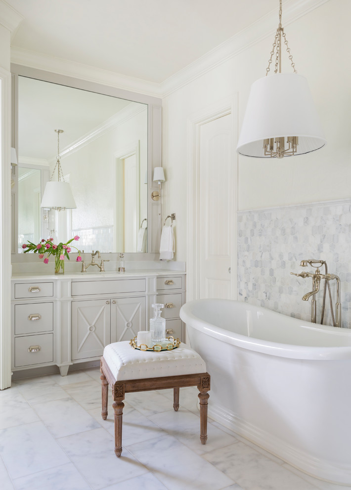 Inspiration pour une salle de bain principale traditionnelle avec des portes de placard grises, une baignoire indépendante, un mur blanc, un sol blanc, un plan de toilette blanc et un placard avec porte à panneau encastré.