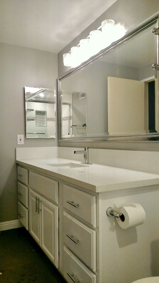Cette photo montre une salle de bain moderne de taille moyenne avec un placard avec porte à panneau surélevé, des portes de placard blanches, une baignoire posée, un combiné douche/baignoire, WC à poser, un carrelage blanc, des carreaux de porcelaine, un mur gris, sol en béton ciré, un lavabo encastré et un plan de toilette en quartz modifié.