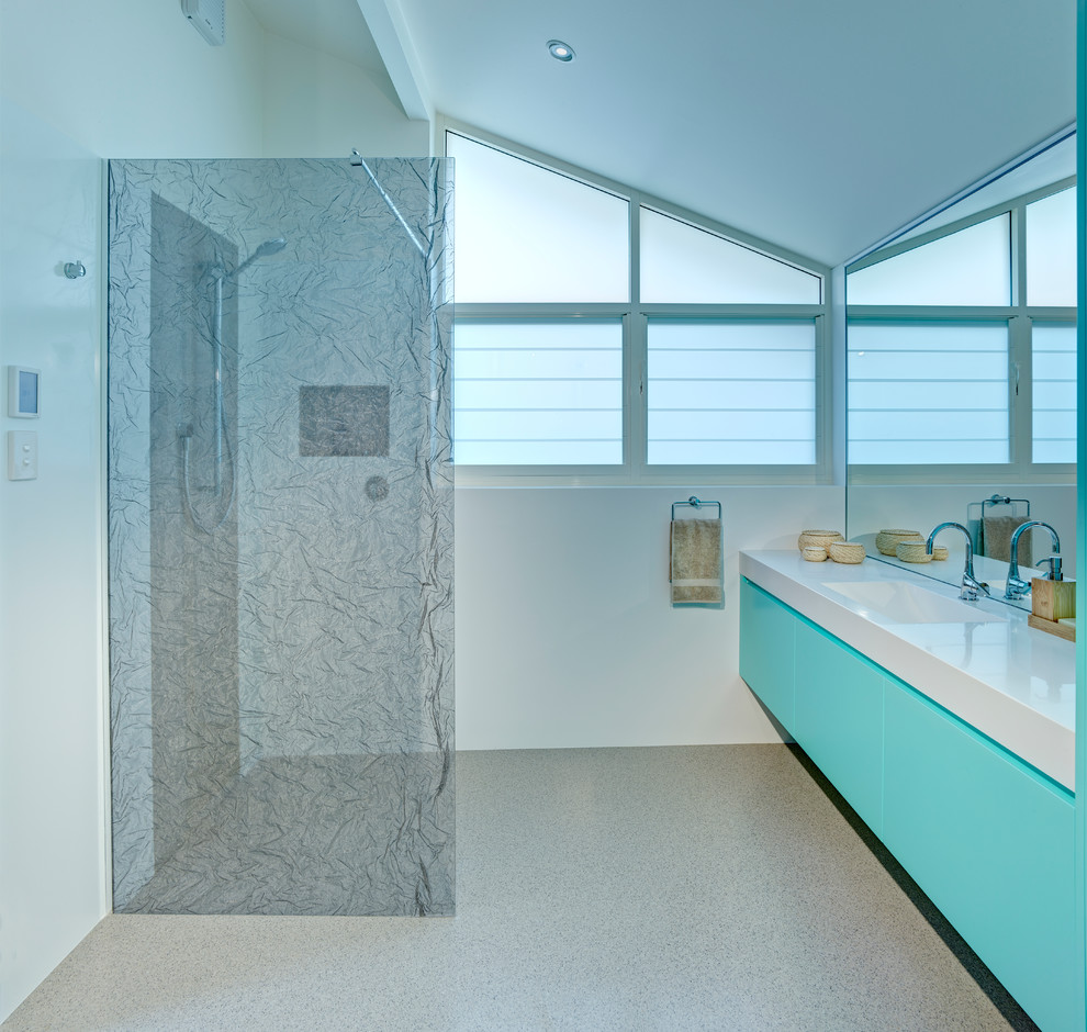 Inredning av ett modernt badrum, med ett integrerad handfat, blå skåp och en öppen dusch