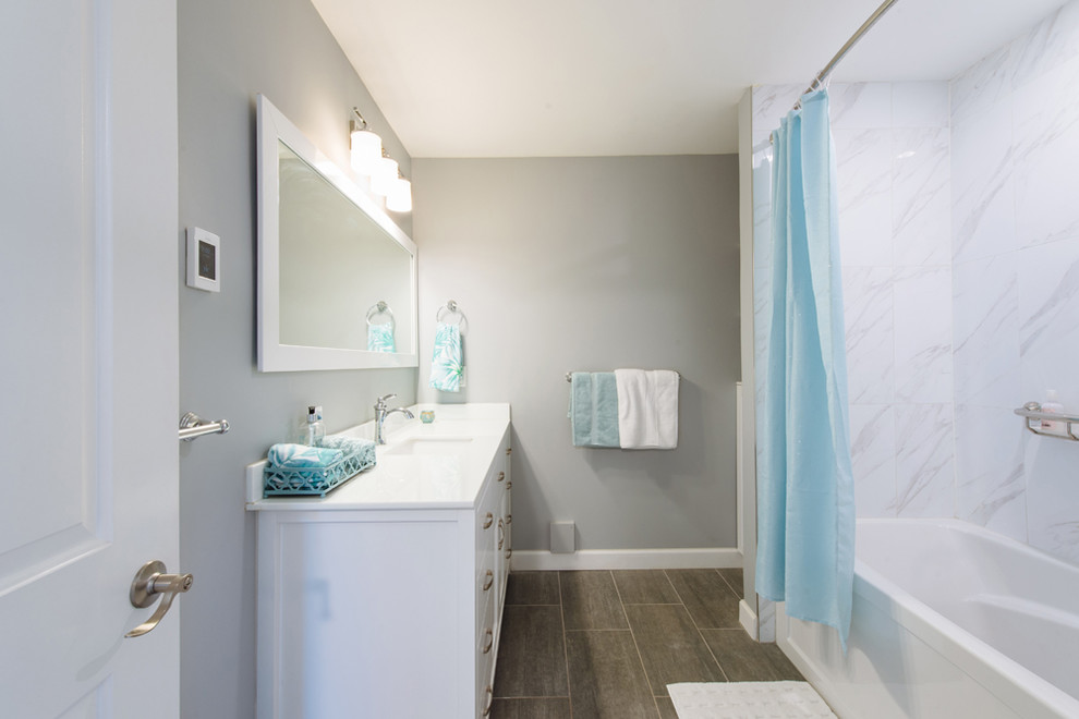 Medium sized rural shower room bathroom in Vancouver with shaker cabinets, white cabinets, an alcove bath, a shower/bath combination, a one-piece toilet, white tiles, porcelain tiles, blue walls, vinyl flooring, a submerged sink, glass worktops, grey floors, a shower curtain and white worktops.