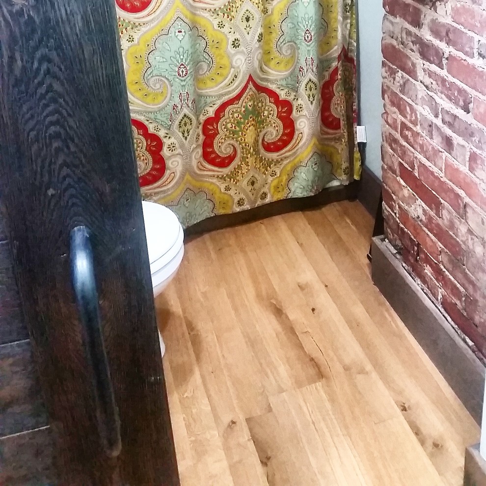 Urban medium tone wood floor bathroom photo in Other with a one-piece toilet and green walls