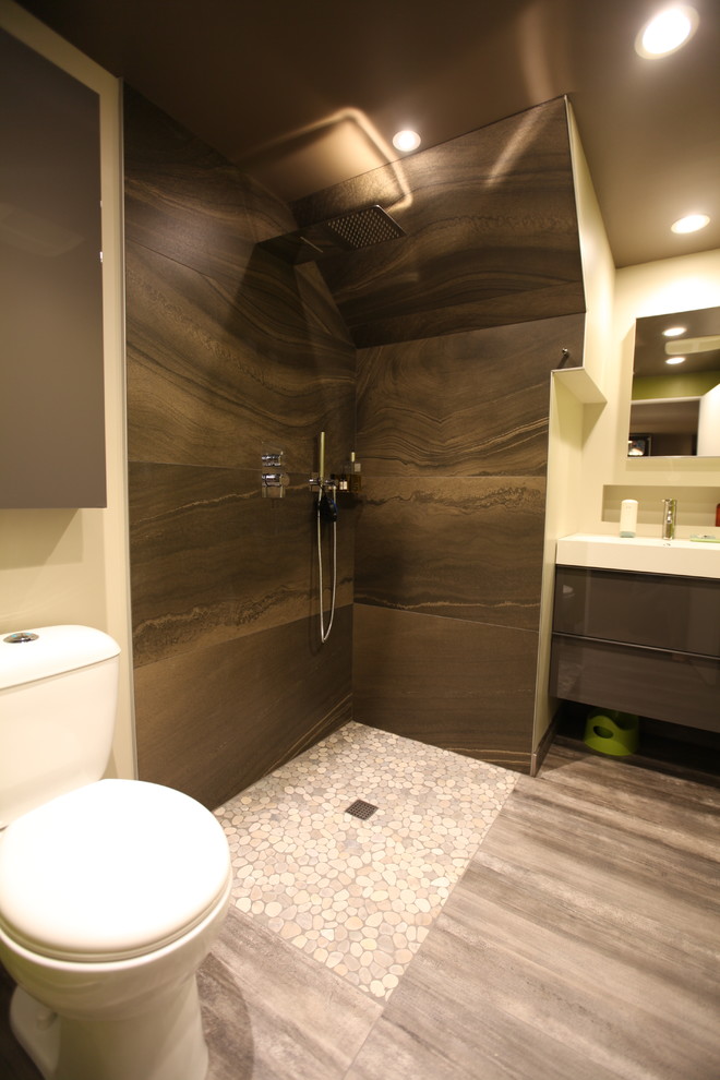 This is an example of a small modern shower room bathroom in Edmonton with flat-panel cabinets, grey cabinets, a corner shower, a two-piece toilet, brown tiles, porcelain tiles, green walls, porcelain flooring, an integrated sink, solid surface worktops, grey floors and a hinged door.