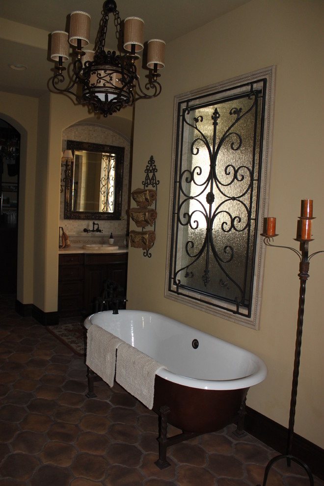 Modelo de cuarto de baño principal mediterráneo de tamaño medio con bañera exenta, paredes beige, suelo de baldosas de terracota, lavabo encastrado y suelo marrón