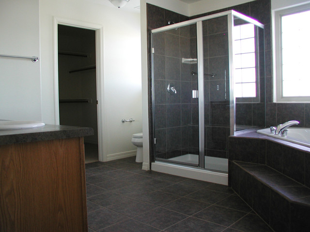 Diseño de cuarto de baño clásico renovado con lavabo encastrado, puertas de armario de madera oscura, bañera encastrada, ducha esquinera, baldosas y/o azulejos grises y paredes blancas