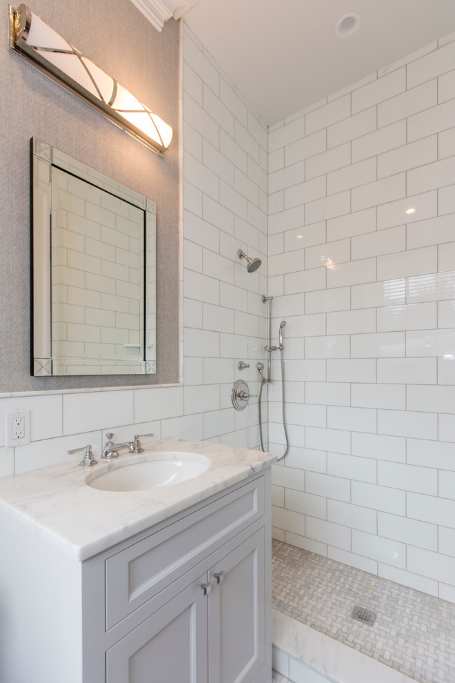 Стильный дизайн: ванная комната в классическом стиле с фасадами с выступающей филенкой, белыми фасадами, угловым душем, унитазом-моноблоком, белой плиткой, керамической плиткой, серыми стенами, полом из мозаичной плитки, врезной раковиной и мраморной столешницей - последний тренд
