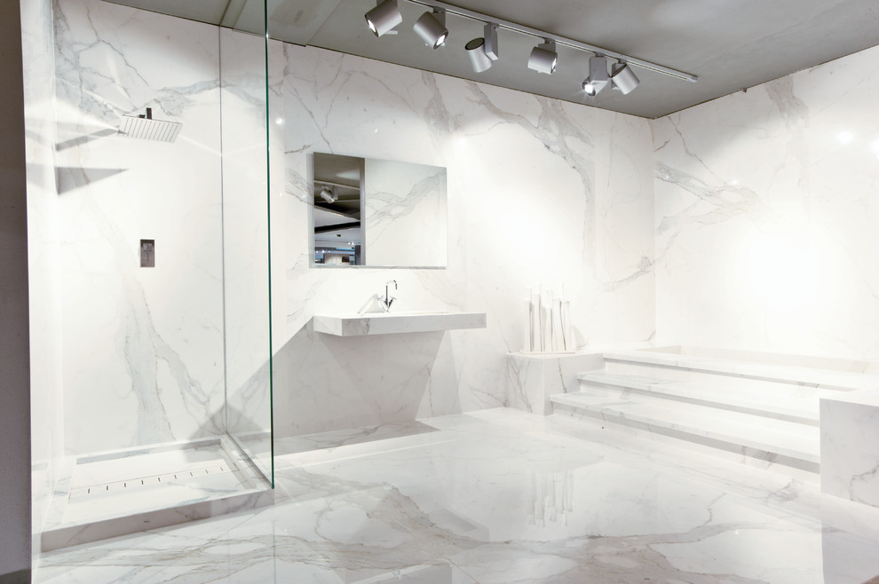 Ejemplo de cuarto de baño principal minimalista grande con bañera esquinera, ducha esquinera, losas de piedra, suelo de mármol, lavabo integrado y encimera de mármol