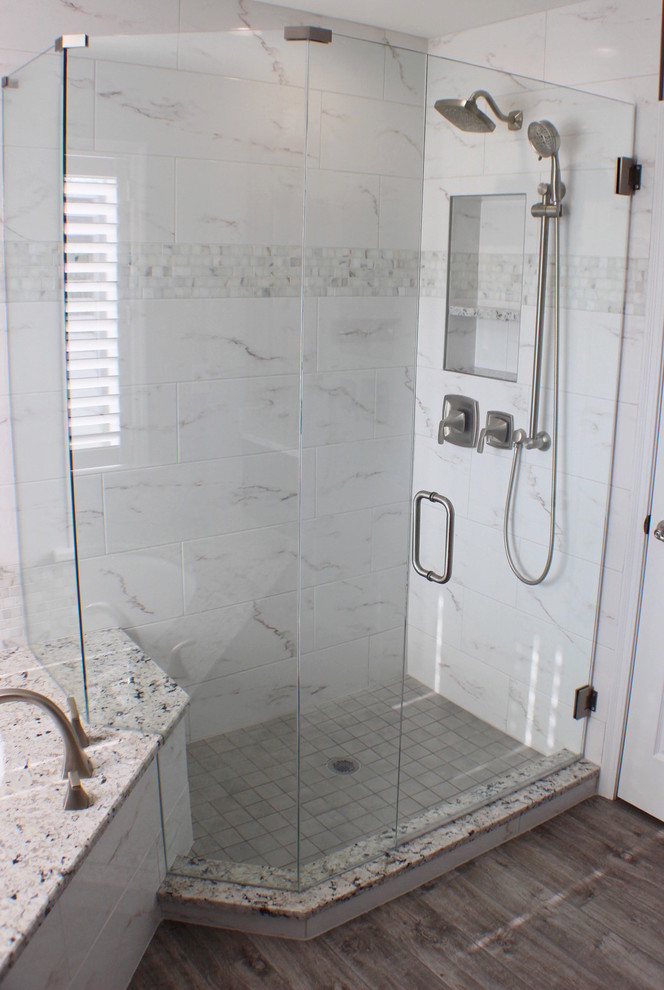 Пример оригинального дизайна: главная ванная комната среднего размера в стиле неоклассика (современная классика) с белой плиткой, серыми стенами, полновстраиваемой ванной, угловым душем, мраморной плиткой, темным паркетным полом, коричневым полом и душем с распашными дверями