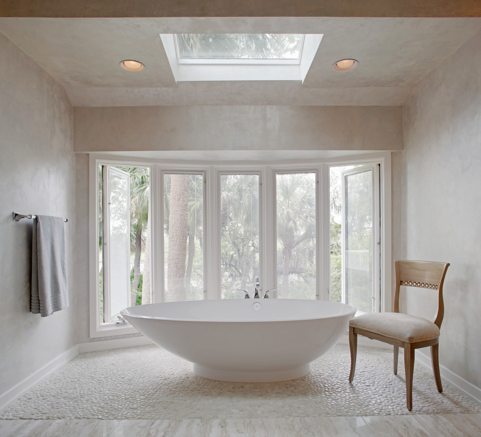 This is an example of a contemporary bathroom in Charleston with a freestanding bath and pebble tile flooring.