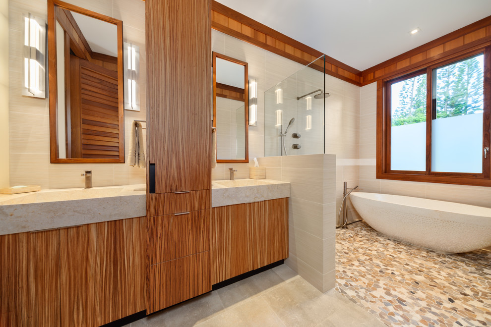 ハワイにあるラグジュアリーな巨大なモダンスタイルのおしゃれなマスターバスルーム (フラットパネル扉のキャビネット、中間色木目調キャビネット、置き型浴槽、オープン型シャワー、ベージュのタイル、セラミックタイル、ベージュの壁、ライムストーンの床、一体型シンク、大理石の洗面台、ベージュの床、オープンシャワー) の写真