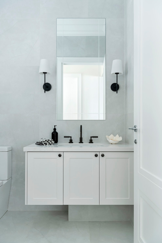 Klassisk inredning av ett stort vit vitt badrum med dusch, med skåp i shakerstil, vita skåp, en toalettstol med hel cisternkåpa, grå kakel, porslinskakel, grå väggar, klinkergolv i porslin, ett undermonterad handfat och grått golv