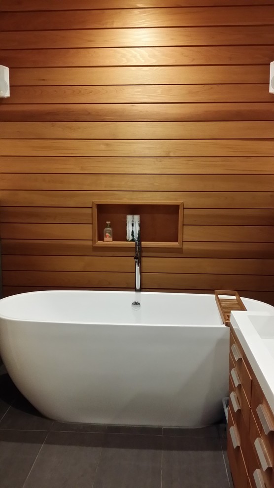 Immagine di una stanza da bagno moderna con ante in legno scuro, top in quarzite, vasca freestanding e pavimento in gres porcellanato