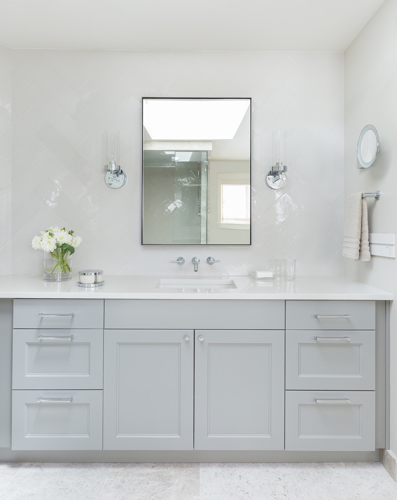 Idéer för att renovera ett mellanstort vintage vit vitt badrum med dusch, med luckor med infälld panel, grå skåp, vit kakel, keramikplattor, vita väggar, klinkergolv i keramik, ett undermonterad handfat, bänkskiva i akrylsten och vitt golv