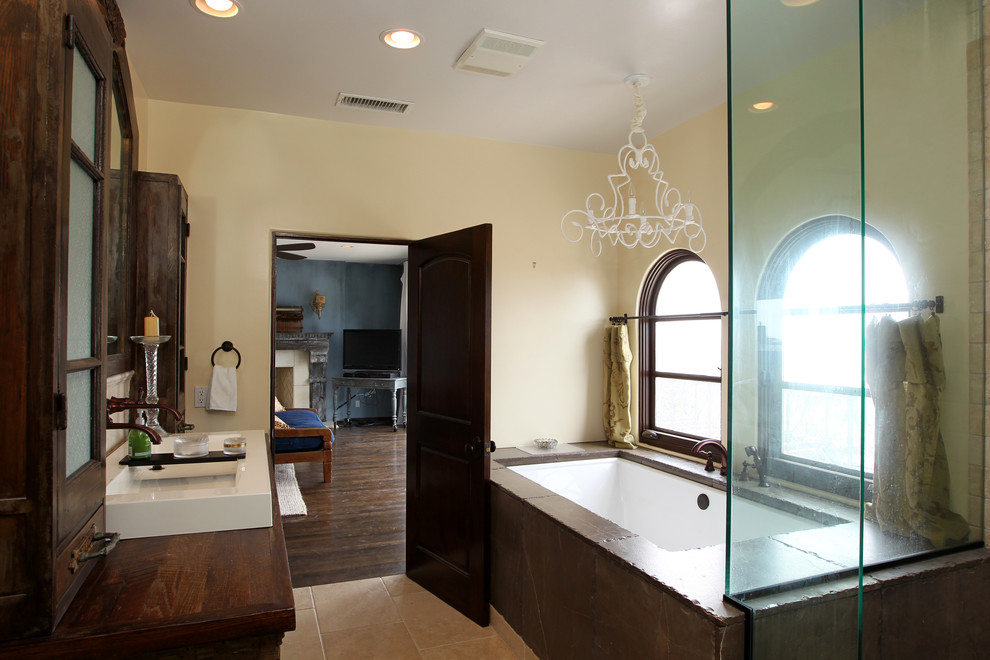 Large tuscan master beige tile and travertine tile travertine floor and beige floor double shower photo in Los Angeles with beige walls, wood countertops, furniture-like cabinets, distressed cabinets, an undermount tub, a two-piece toilet, a vessel sink and a hinged shower door
