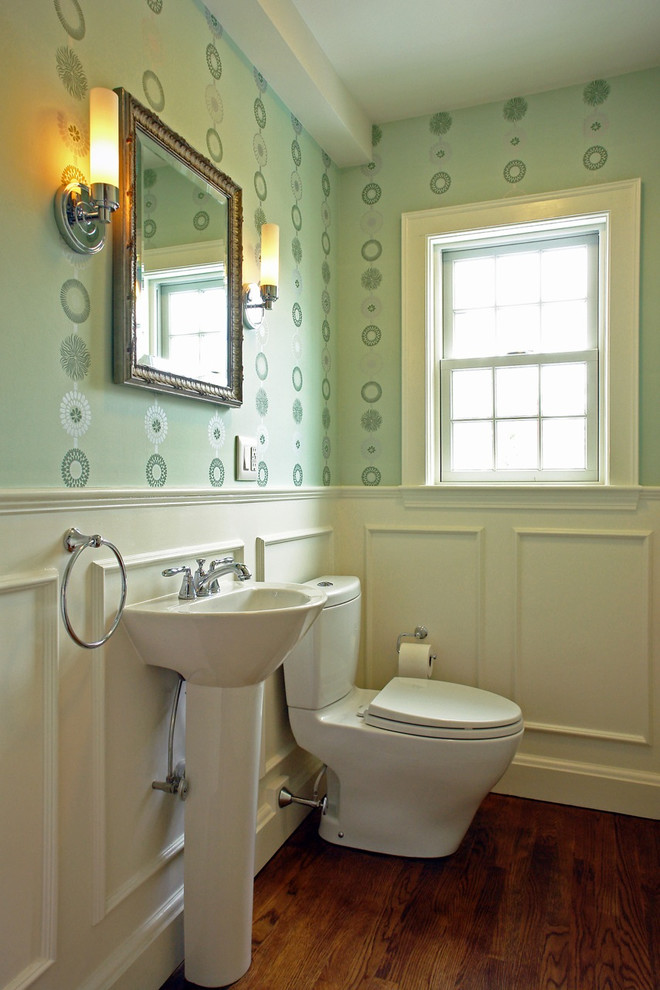 Foto på ett vintage badrum, med ett piedestal handfat, en toalettstol med separat cisternkåpa, gröna väggar och mörkt trägolv