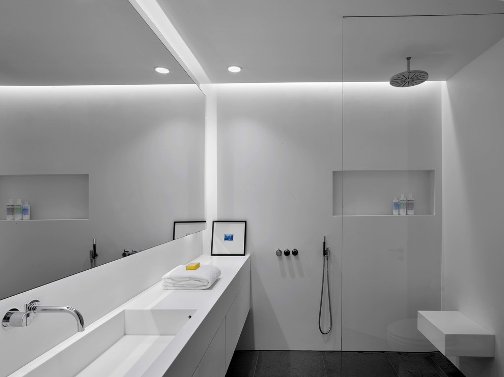 Modernes Badezimmer mit flächenbündigen Schrankfronten, weißen Schränken, bodengleicher Dusche, weißer Wandfarbe, integriertem Waschbecken, grauem Boden, offener Dusche und weißer Waschtischplatte in Santa Barbara