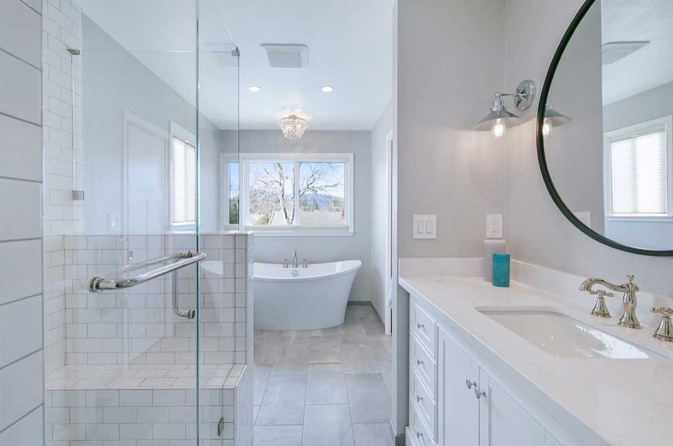 Klassisk inredning av ett mellanstort vit vitt en-suite badrum, med möbel-liknande, vita skåp, ett fristående badkar, en dusch i en alkov, en toalettstol med separat cisternkåpa, vit kakel, tunnelbanekakel, grå väggar, klinkergolv i porslin, ett undermonterad handfat, bänkskiva i kvarts, grått golv och dusch med gångjärnsdörr