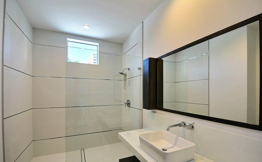 Modern inredning av ett mellanstort badrum, med ett fristående handfat, luckor med glaspanel, vita skåp, bänkskiva i kvartsit, en öppen dusch, en vägghängd toalettstol, vit kakel, vita väggar och klinkergolv i porslin