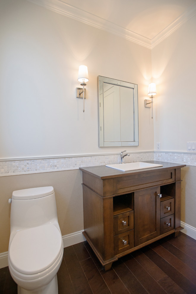 Foto på ett litet funkis badrum med dusch, med skåp i shakerstil, skåp i mellenmörkt trä, en toalettstol med hel cisternkåpa, flerfärgade väggar, mörkt trägolv, ett nedsänkt handfat och träbänkskiva