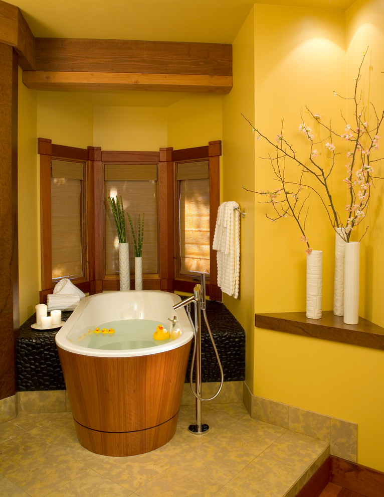 На фото: ванная комната в восточном стиле с отдельно стоящей ванной, желтыми стенами и бежевым полом с