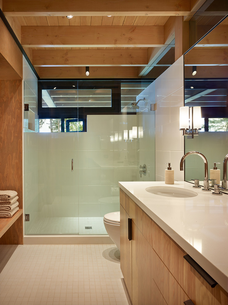 Пример оригинального дизайна: ванная комната в современном стиле с плоскими фасадами, фасадами цвета дерева среднего тона, душем в нише, белой плиткой, врезной раковиной, белым полом, душем с распашными дверями и белой столешницей