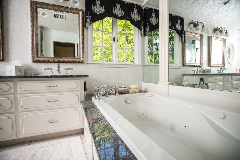 Klassisk inredning av ett mellanstort en-suite badrum, med möbel-liknande, vita skåp, ett platsbyggt badkar, vit kakel, keramikplattor, klinkergolv i keramik, ett integrerad handfat, granitbänkskiva och grå väggar