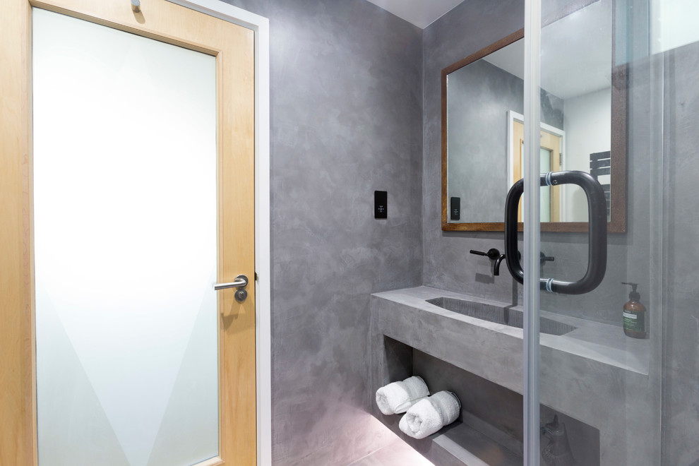 Inspiration för små industriella en-suite badrum, med luckor med profilerade fronter, bruna skåp, en öppen dusch, en vägghängd toalettstol, grå kakel, grå väggar, betonggolv, ett väggmonterat handfat, grått golv och dusch med gångjärnsdörr