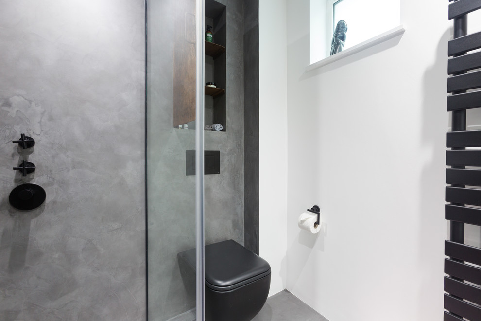 Inspiration for a small urban ensuite bathroom in London with beaded cabinets, brown cabinets, a walk-in shower, a wall mounted toilet, grey tiles, grey walls, concrete flooring, a wall-mounted sink, grey floors and a hinged door.