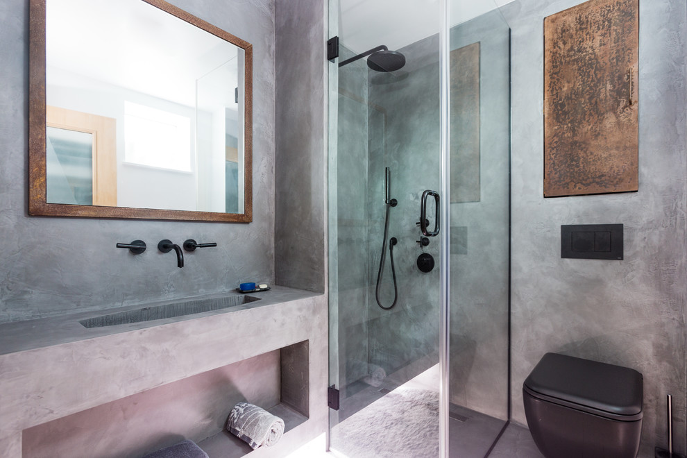 Design ideas for a small industrial ensuite bathroom in London with beaded cabinets, brown cabinets, a walk-in shower, a wall mounted toilet, grey tiles, grey walls, concrete flooring, a wall-mounted sink, grey floors and a hinged door.