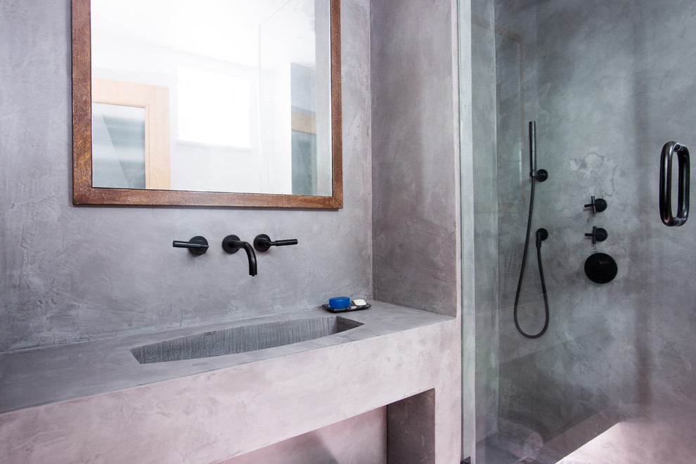 This is an example of a small industrial ensuite bathroom in London with beaded cabinets, brown cabinets, a walk-in shower, a wall mounted toilet, grey tiles, grey walls, concrete flooring, a wall-mounted sink, grey floors and a hinged door.