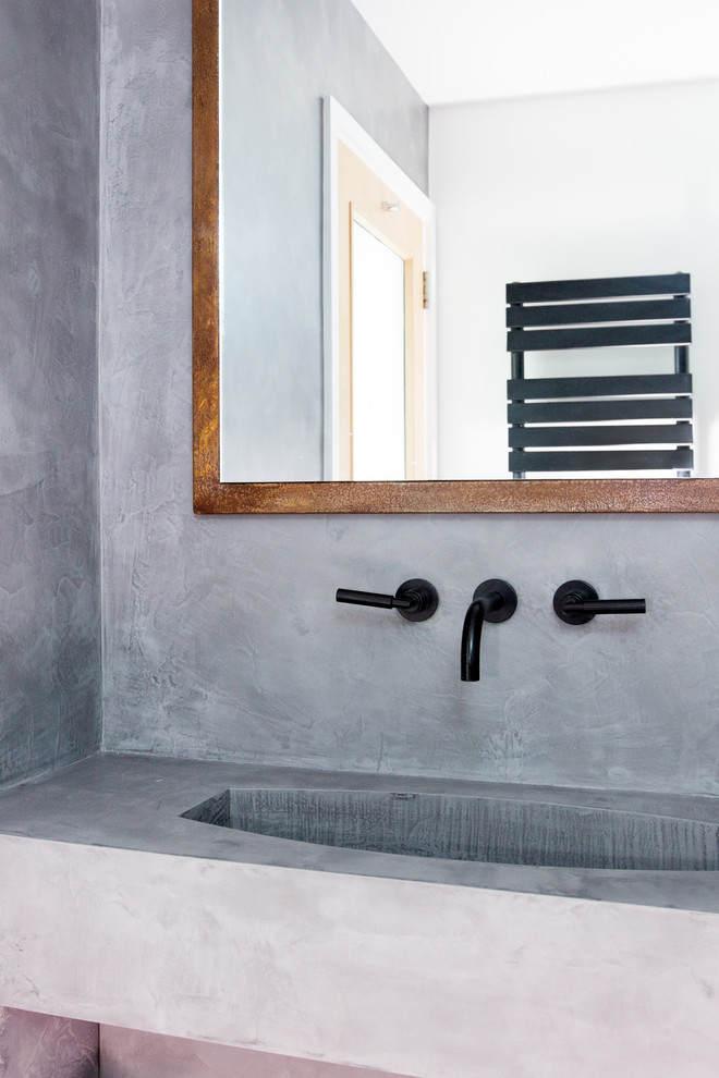 Bild på ett litet industriellt en-suite badrum, med luckor med profilerade fronter, bruna skåp, en öppen dusch, en vägghängd toalettstol, grå kakel, grå väggar, betonggolv, ett väggmonterat handfat, grått golv och dusch med gångjärnsdörr