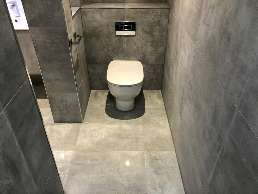 Aménagement d'une salle de bain moderne avec des portes de placard grises, une baignoire indépendante, une douche ouverte, WC à poser, un carrelage gris, des carreaux de porcelaine, un sol en carrelage de porcelaine, un plan de toilette en carrelage, un sol gris et un plan de toilette gris.