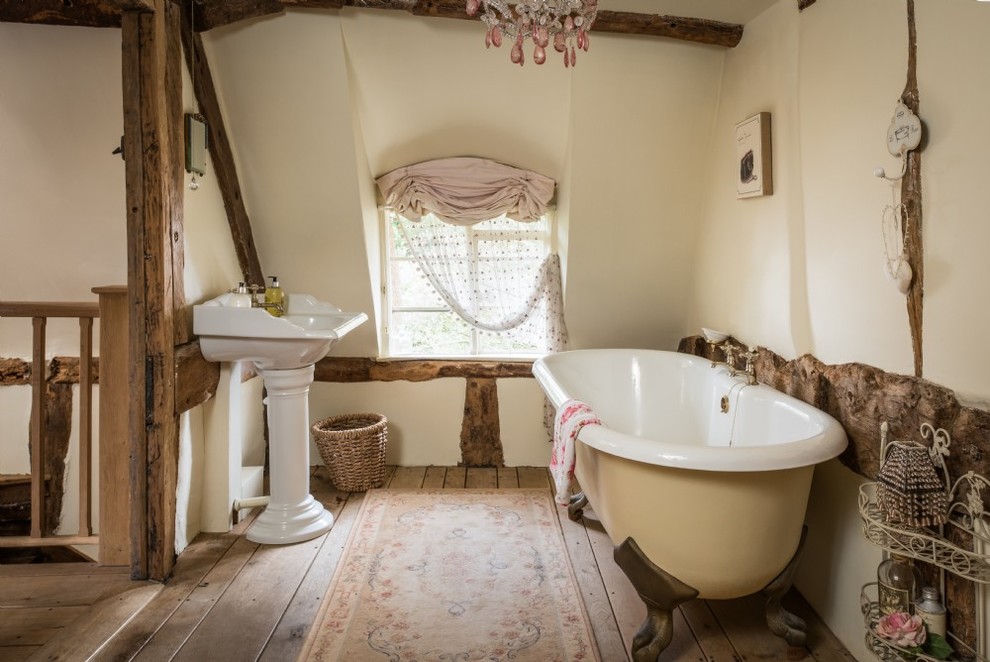 Foto de cuarto de baño infantil rústico de tamaño medio con bañera con patas, paredes blancas, suelo de madera en tonos medios, lavabo con pedestal y suelo beige