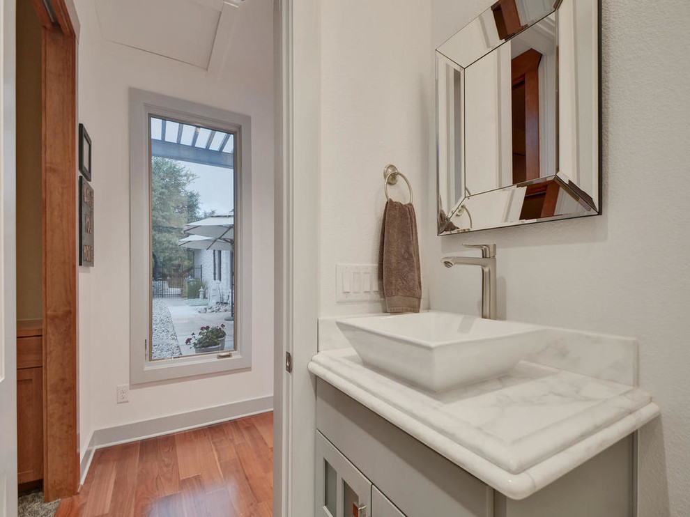 Mittelgroßes Klassisches Duschbad mit braunem Holzboden, Aufsatzwaschbecken, schwarzem Boden, verzierten Schränken, grauen Schränken und Marmor-Waschbecken/Waschtisch in Austin