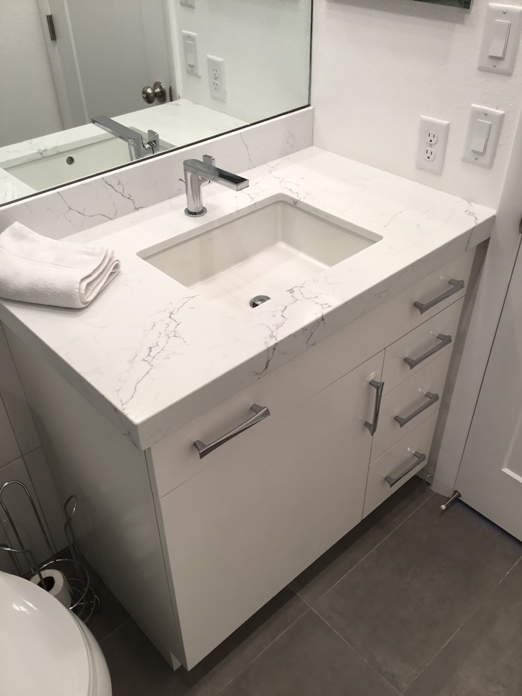 Doorless shower - contemporary white tile and ceramic tile ceramic tile and gray floor doorless shower idea in Salt Lake City with flat-panel cabinets, white cabinets, a two-piece toilet, white walls, an undermount sink, quartz countertops and a hinged shower door